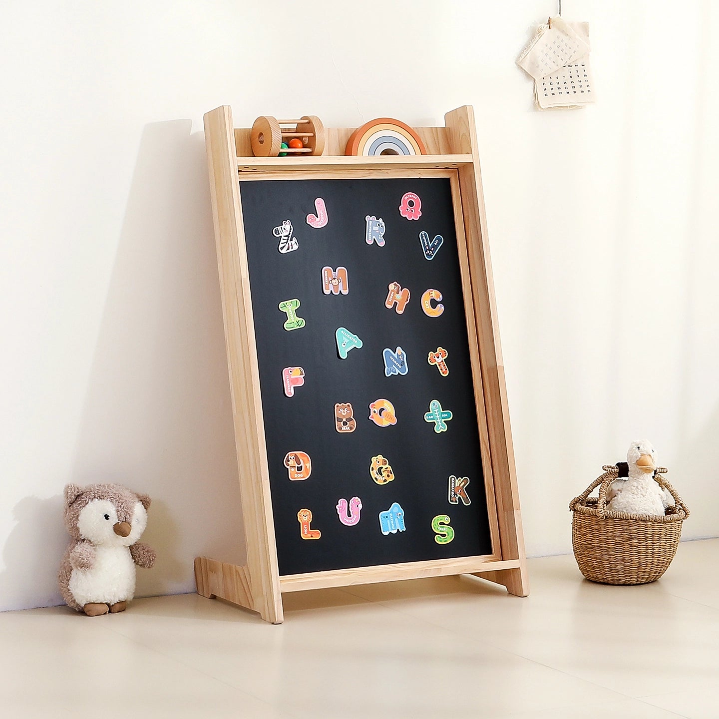 Three-quarter view of the solid pine magnetic chalkboard standing alone and holding colorful letter magnets