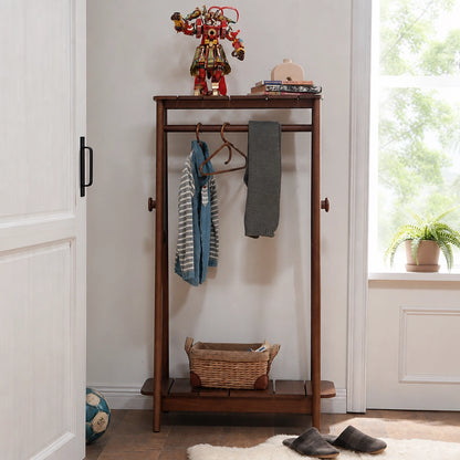 Front view of a dark finish adjustable kids clothing rack with hanging shirts and a lower basket