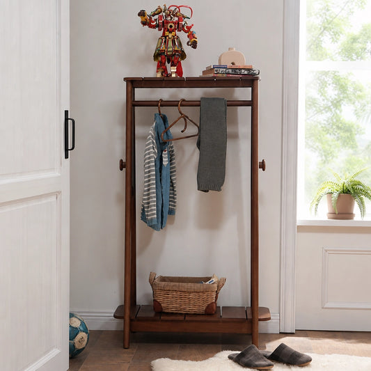 Front view of a dark finish adjustable kids clothing rack with hanging shirts and a lower basket
