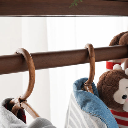 Close-up of a wooden clothes hanger on the dark finish hanging rail of a kids clothing rack