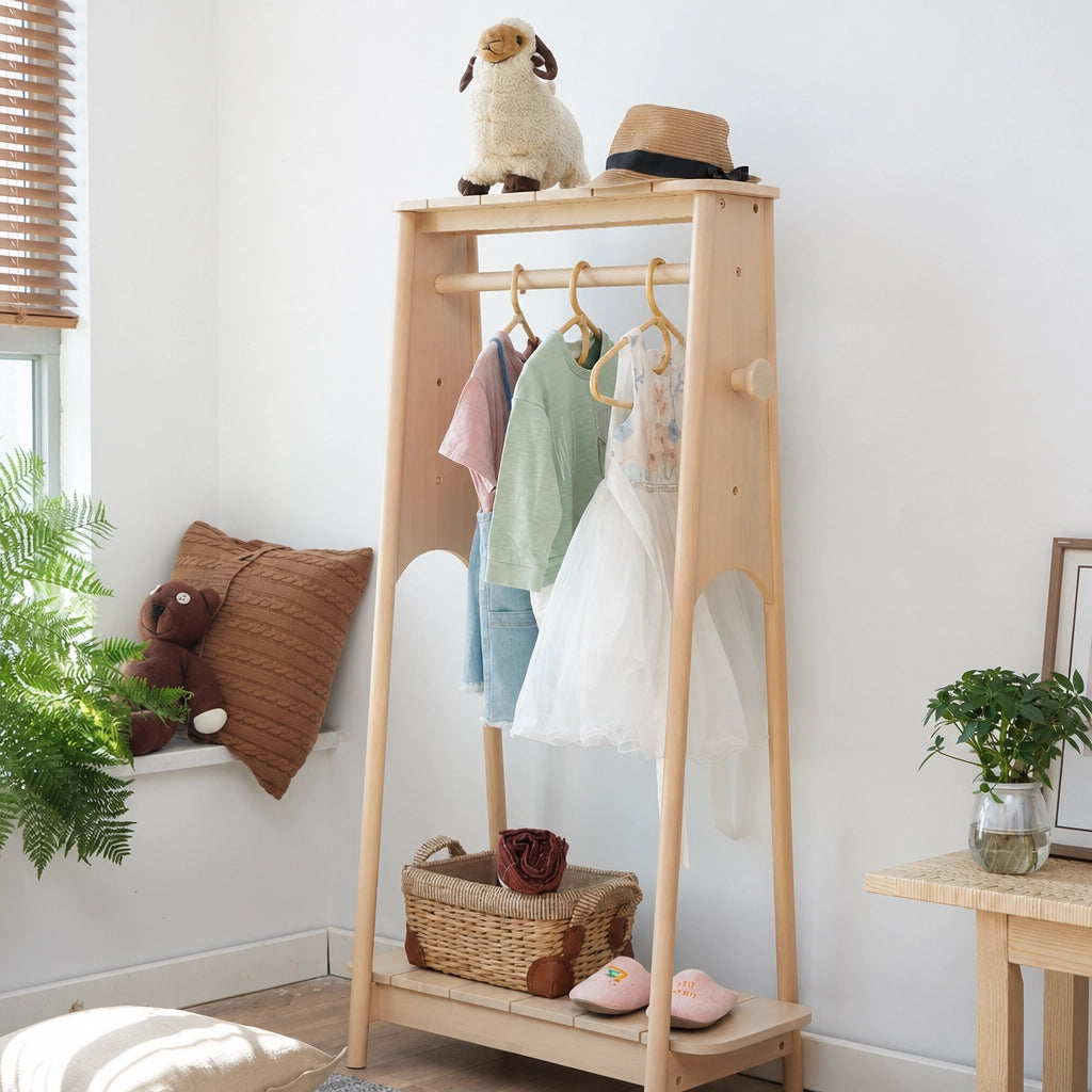 Angled view of a light wood adjustable kids clothing rack filled with a dress and sweaters