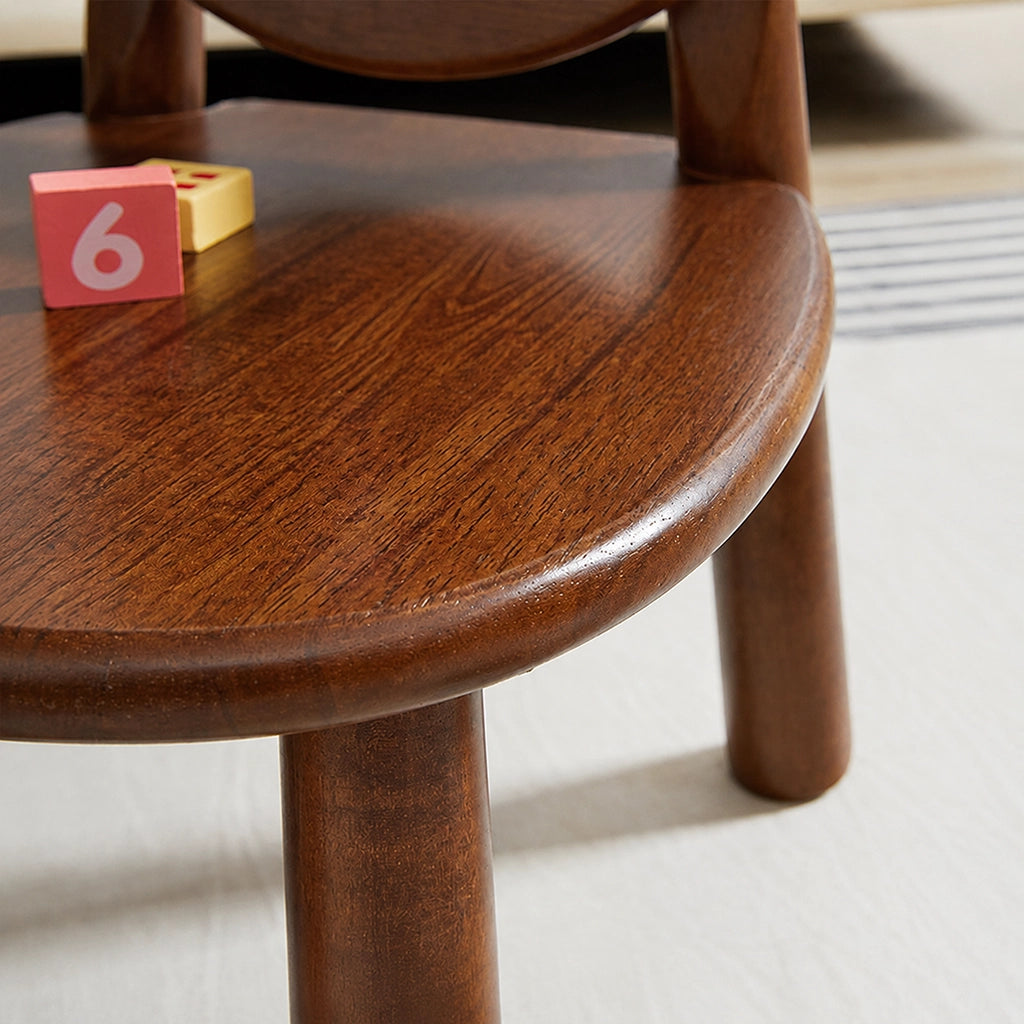 Close-up of the smooth dark wood grain surface and rounded edge of the toddler chair seat