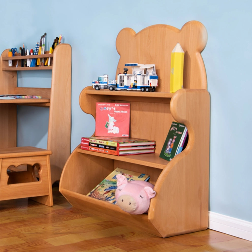 Angled view of a solid beech wood kids bookshelf styled with books and toys next to a children's wooden desk