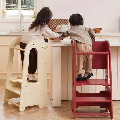 Rear view of two children standing on birch plywood step stools to reach a kitchen counter island