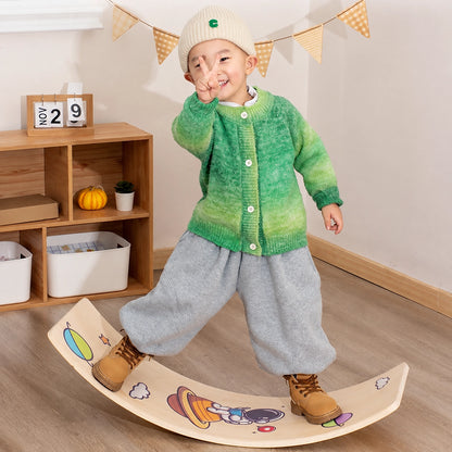 Young child standing on a multi-layer plywood curved balance board with space graphics