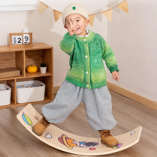Young child standing on a multi-layer plywood curved balance board with space graphics