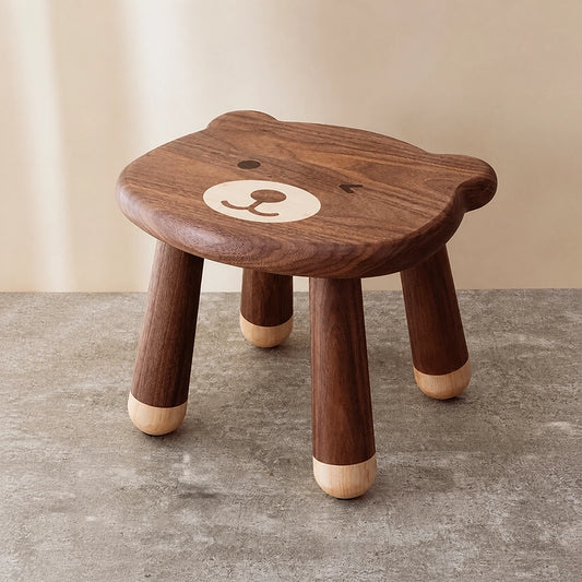 Three-quarter view of a solid black walnut kids stool with a cute bear face design on the seat