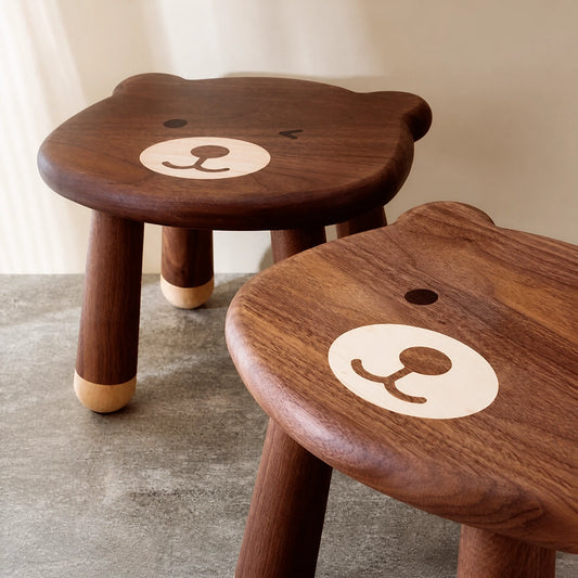 Close-up of two bear stools showing the smooth wooden surface and light-colored nose inlay