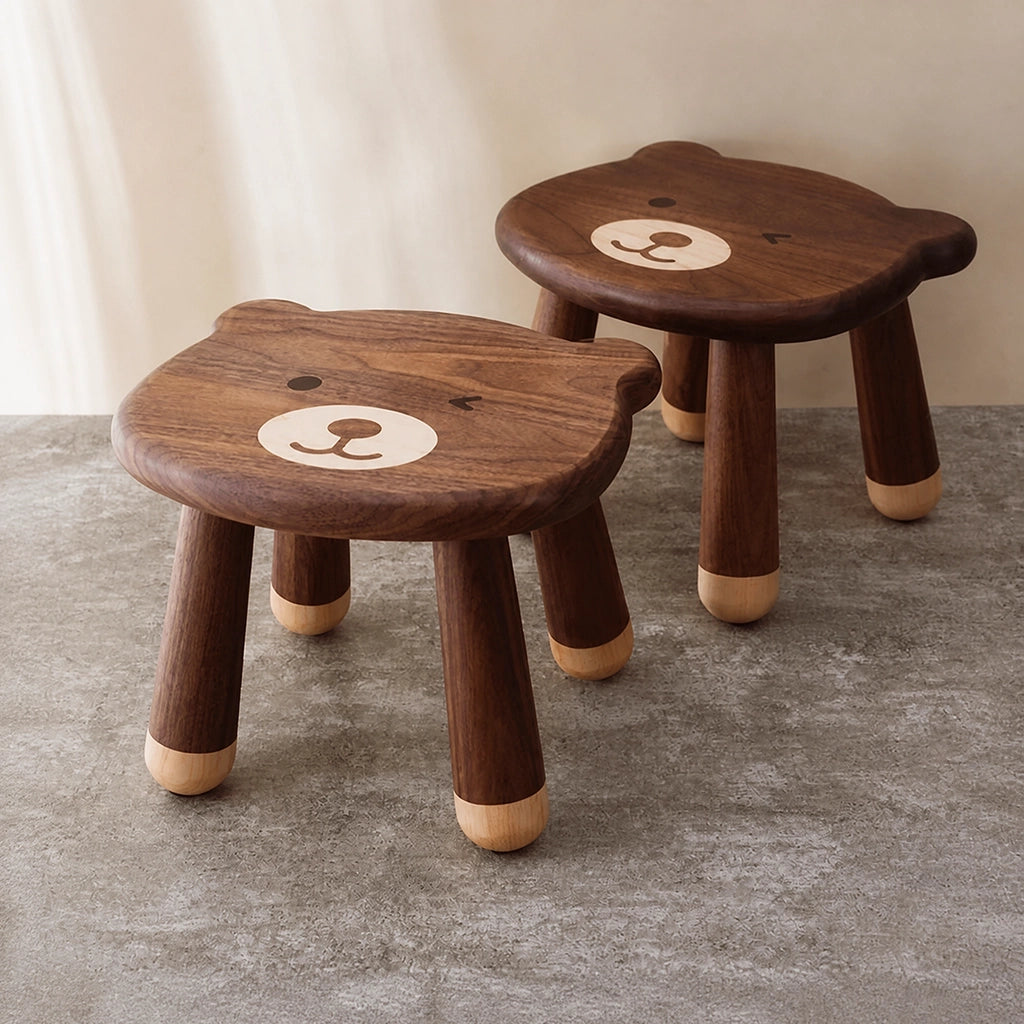 Two solid black walnut bear stools arranged together on a textured gray floor