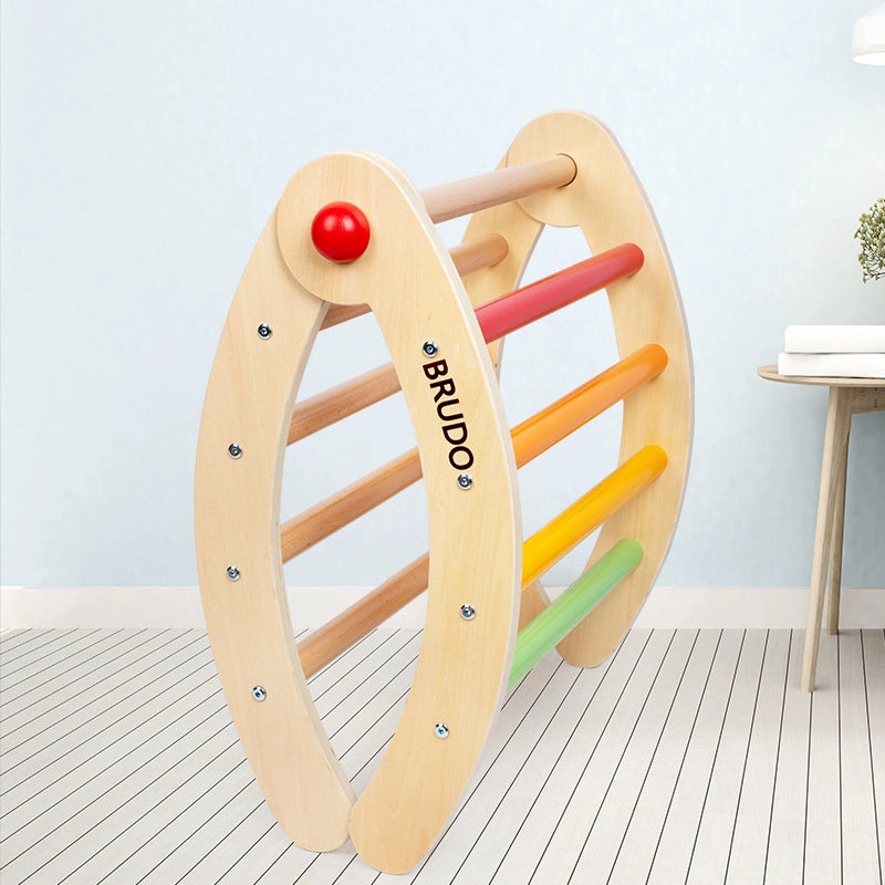 Folded plywood toddler climbing arch standing vertically on a striped floor next to a small table