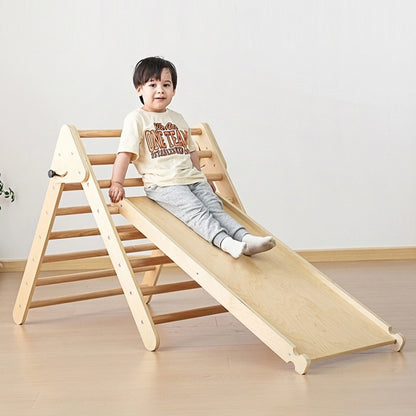 Toddler boy sliding down the smooth wooden ramp attached to a foldable plywood climbing triangle