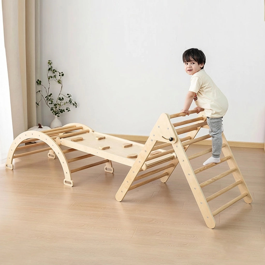 Toddler boy playing on a three-piece plywood climbing set with a triangle ladder, ramp, and arch