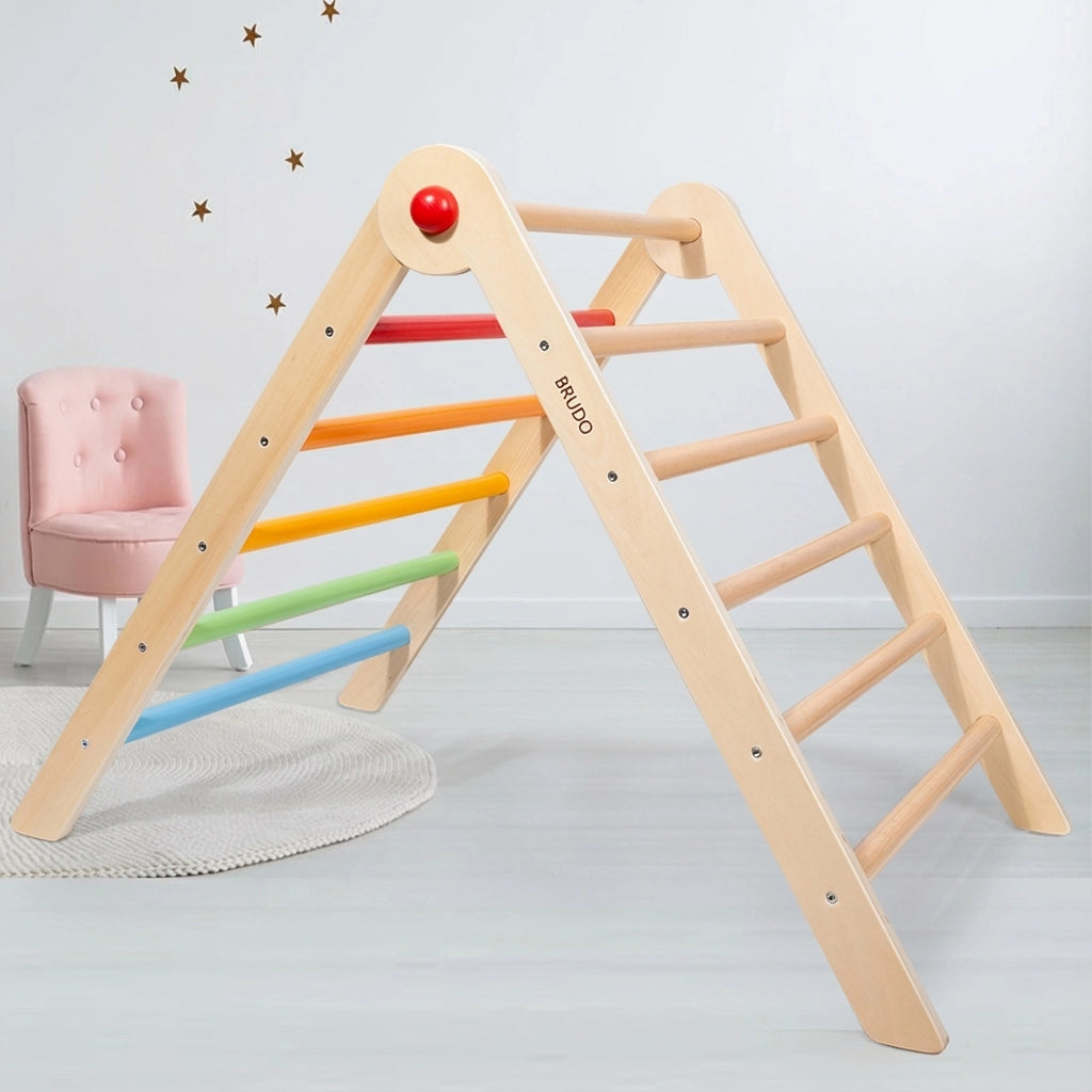 Plywood Montessori climbing triangle with rainbow rungs next to a pink toddler chair in a playroom