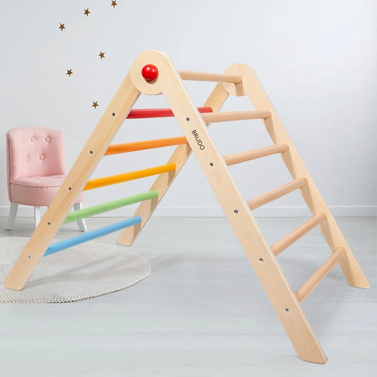 Plywood Montessori climbing triangle with rainbow rungs next to a pink toddler chair in a playroom