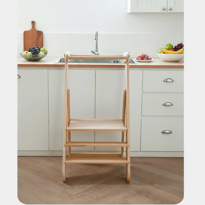 Front view of an empty solid beech wood toddler step stool standing in front of a kitchen sink