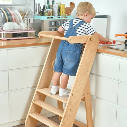 Young boy standing on a wooden toddler step stool to help at a kitchen counter