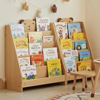 Angled view of two solid beech wood Montessori bear bookshelves filled with children's books beside a small stool