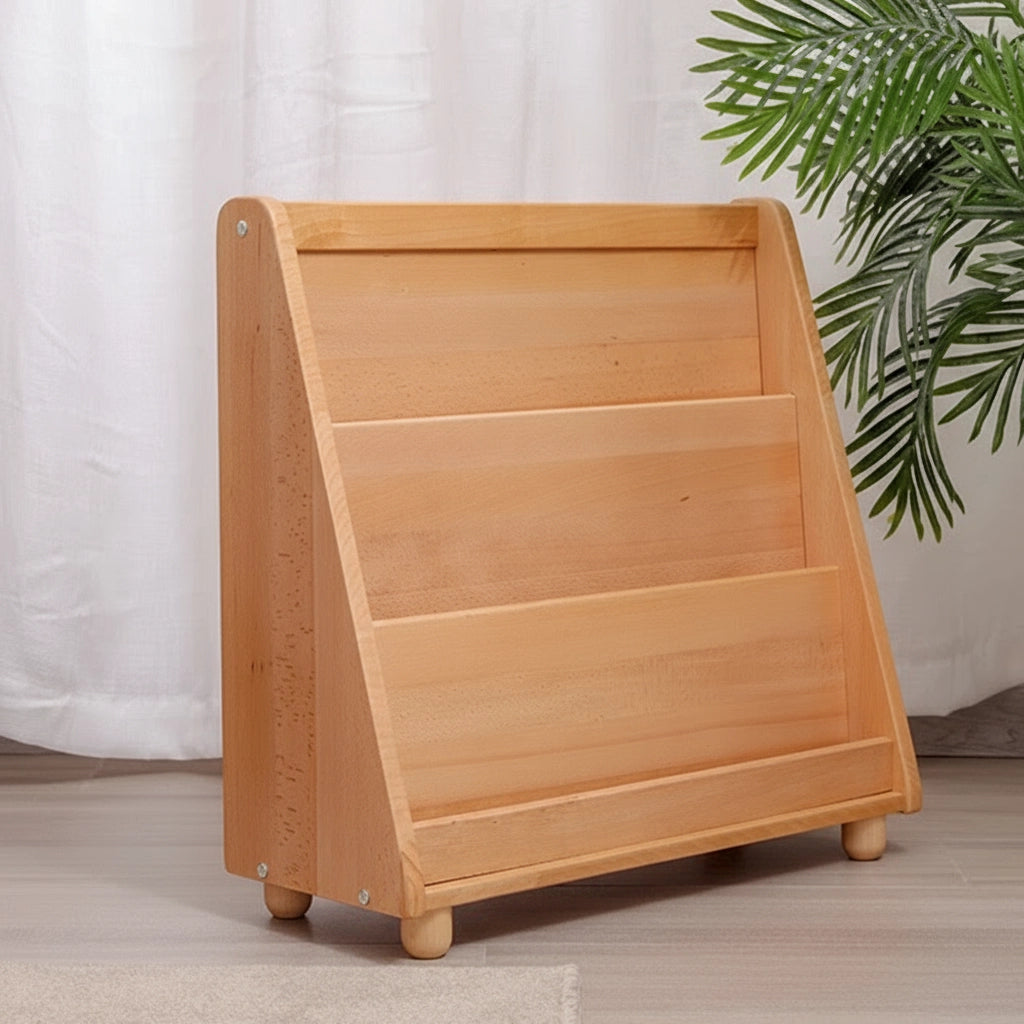 Left-angled view of an empty solid beech wood Montessori book rack beside green plant leaves