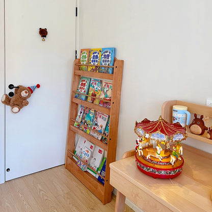Angled view of a rubberwood Montessori book rack next to a small wooden desk holding a red toy carousel