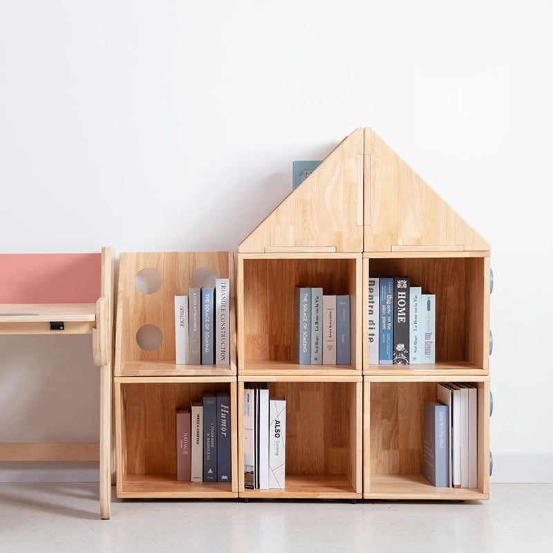 Front view of a solid rubberwood house-shaped kids bookshelf with multiple open cubbies beside a wooden desk