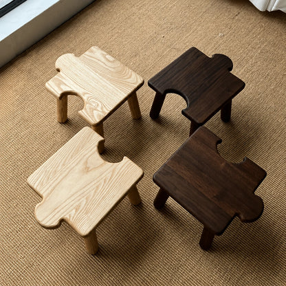 Top-down view of four separate solid wood kids puzzle stools arranged on a woven fiber mat