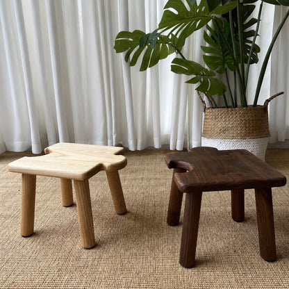 Front view of two interlocking puzzle stools for kids in light and dark solid wood finishes on a woven rug