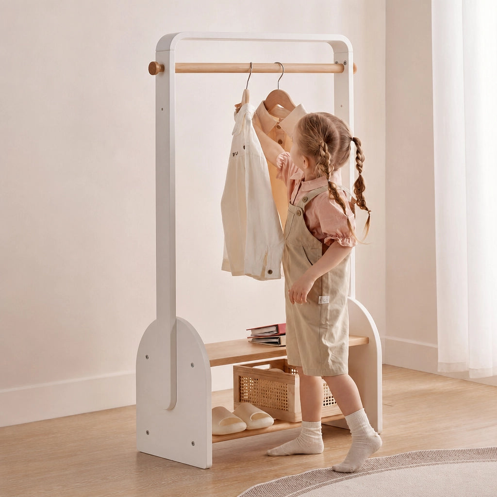 Angled view of a white solid beech wood kids coat rack as a young child hangs up a shirt