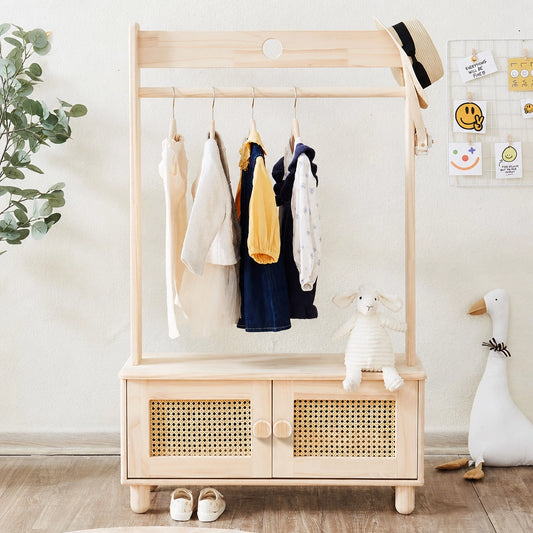Front view of a solid pine kids garment rack with clothes hanging and closed rattan storage cabinet doors
