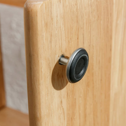 Close-up of a black adjustable leveling foot screw on the side of the wood bookshelf panel