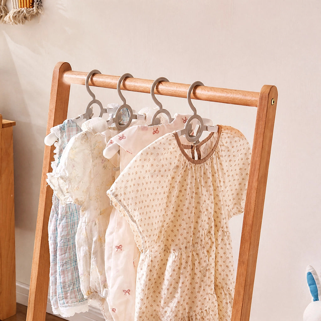 Close-up of children's clothes hanging on the top rail of the solid wood clothing rack