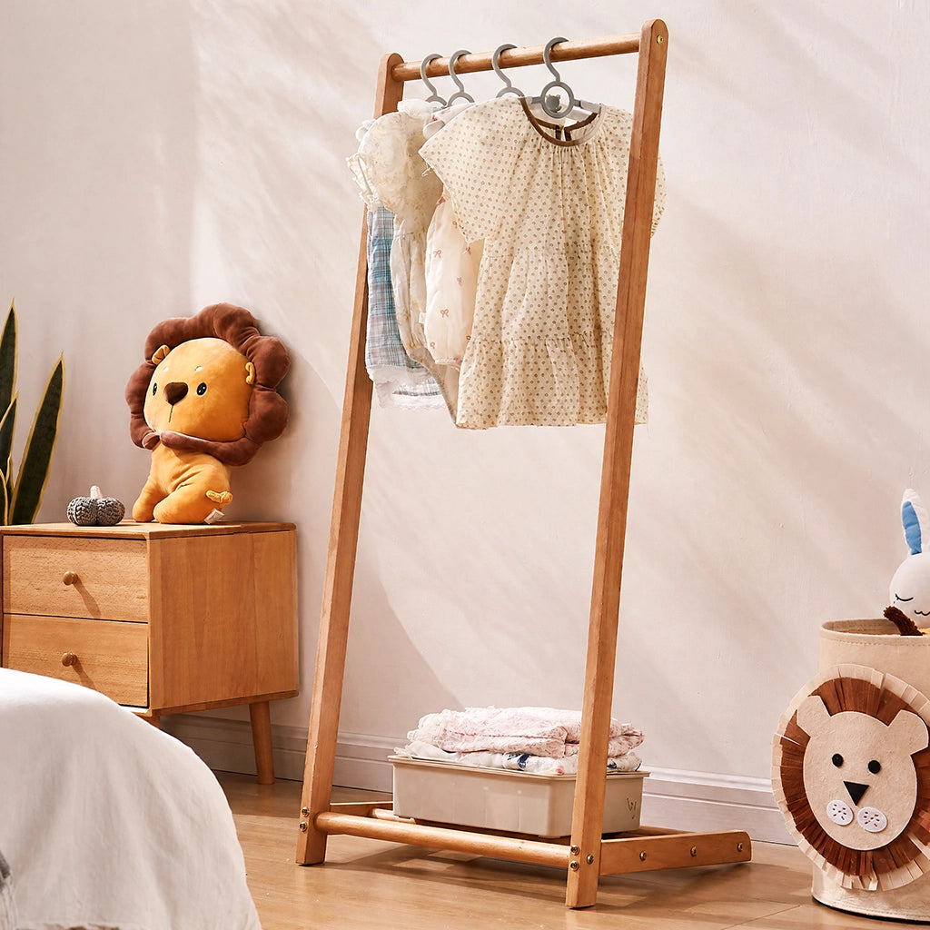 Three-quarter view of the solid wood kids clothing rack holding clothes in a child's bedroom