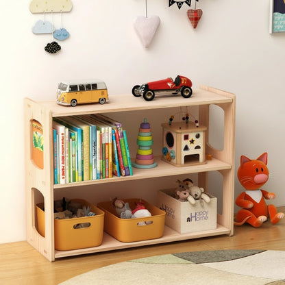 Three-quarter view of a solid pine low bookshelf filled with children's books and toys next to a cat plush doll