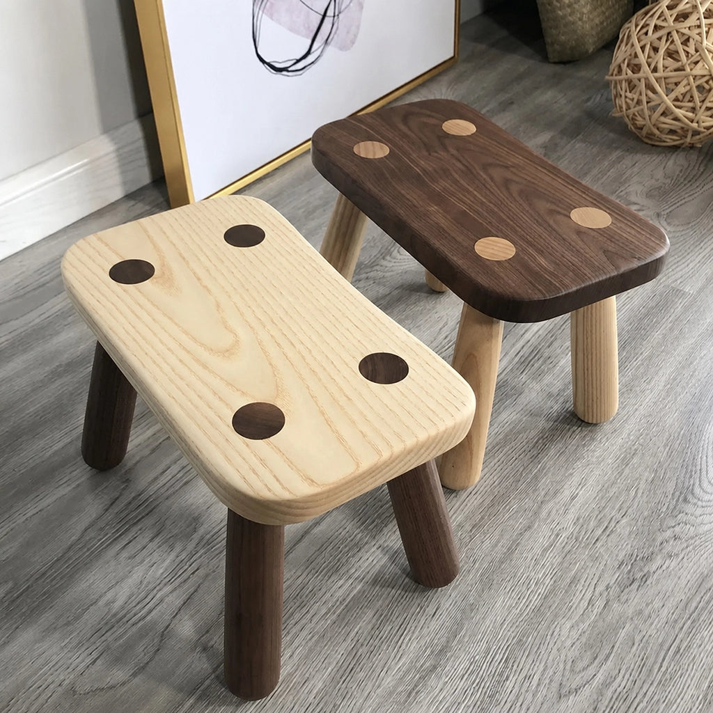 Angled view of two solid wood kids low stools in light and dark natural finishes
