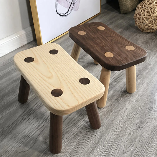 Angled view of two solid wood kids low stools in light and dark natural finishes