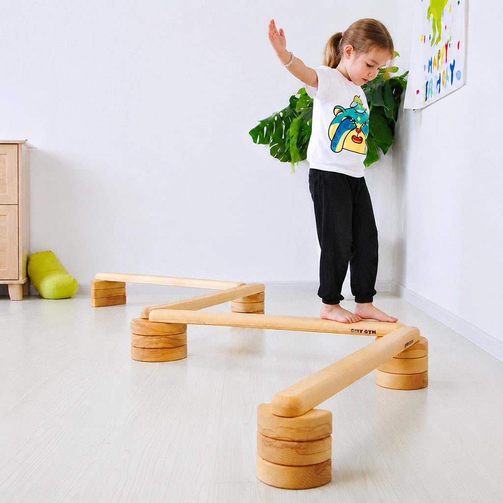 Young girl balancing on a modular solid beech wood balance beam set in a room setting