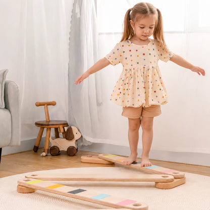 Young girl walking on a modular wooden balance beam in a room setting