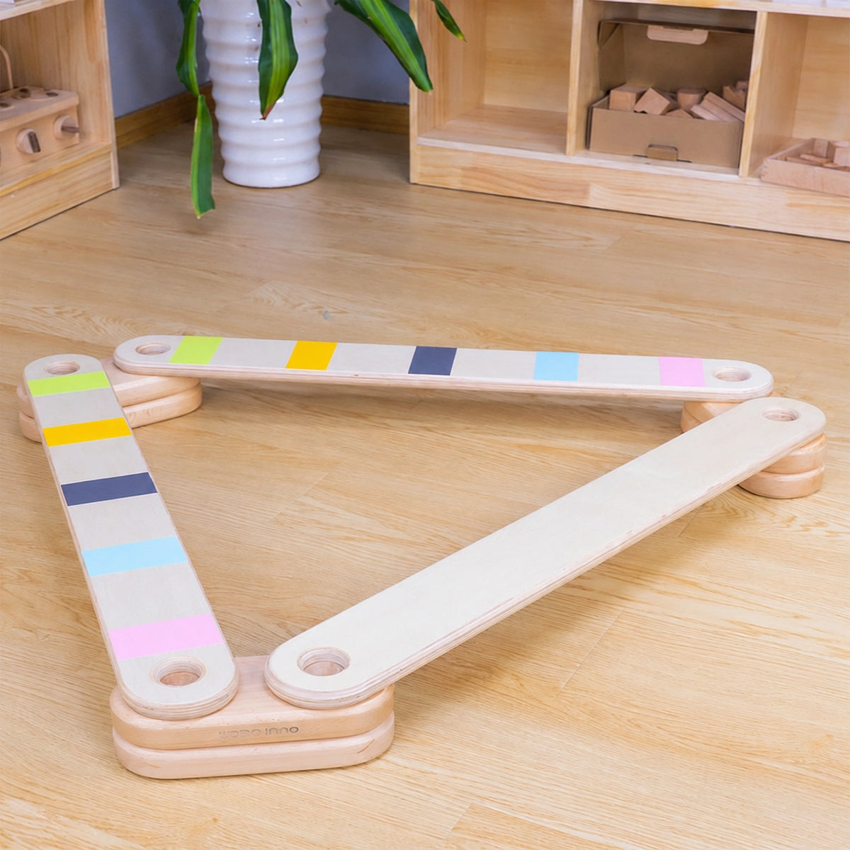 Triangular layout of a modular wooden balance beam set on a wood floor