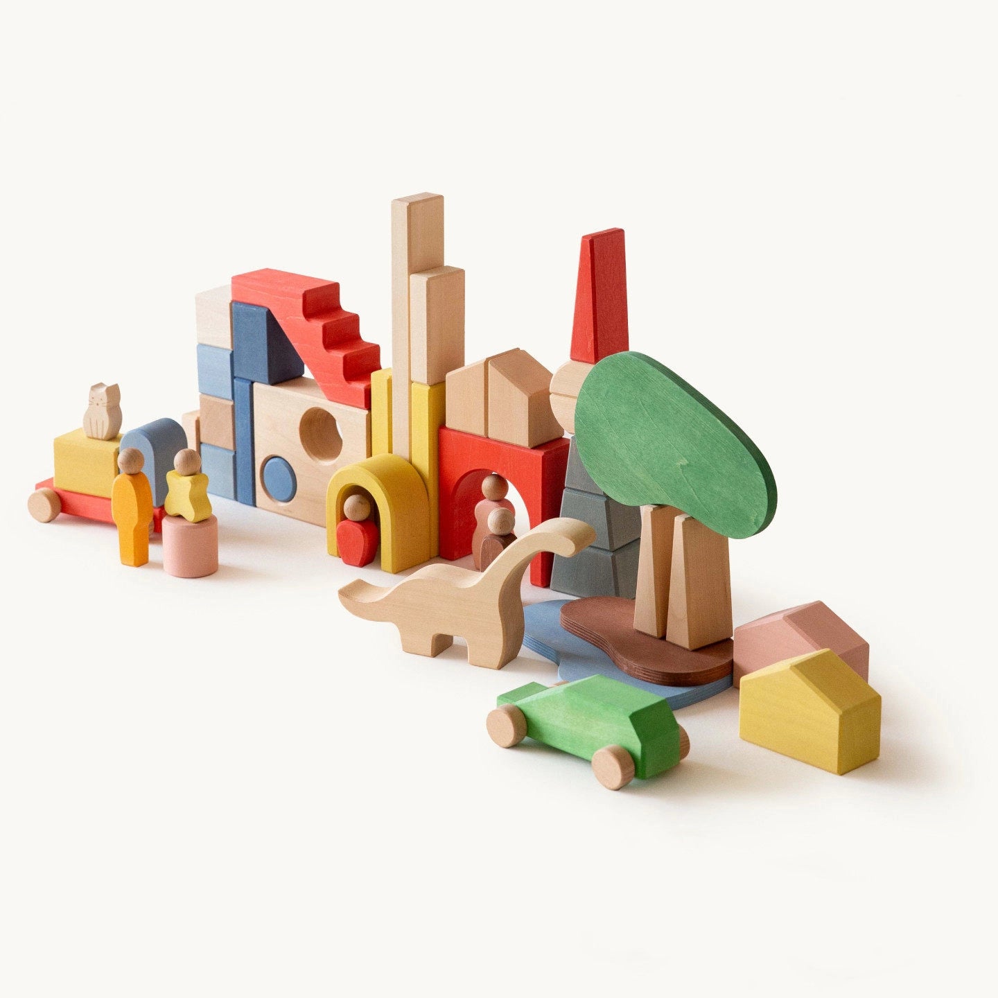 Angled view of a colorful city landscape arranged with wooden blocks, a green tree, and a dinosaur shape