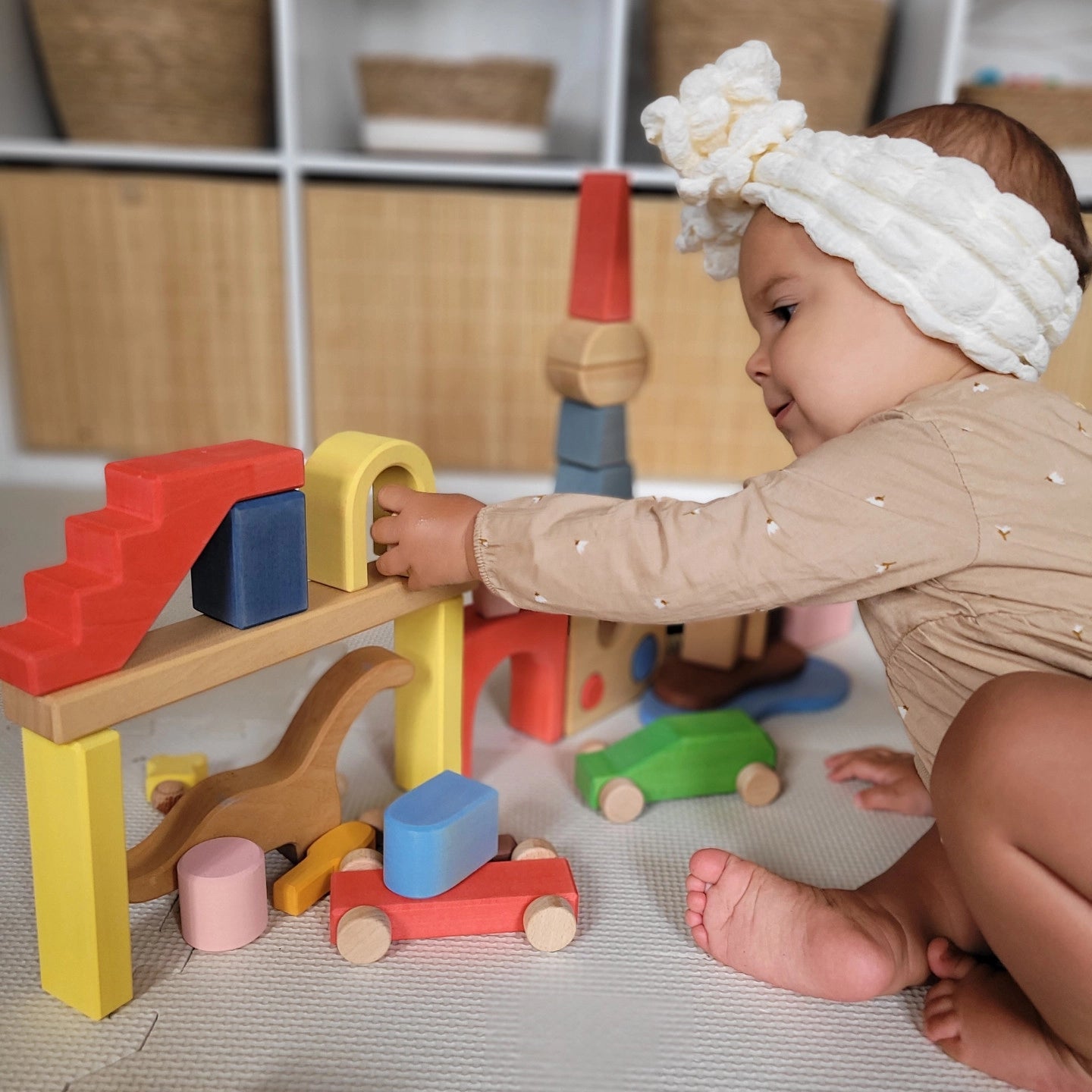 Close-up of a baby girl playing with the colorful solid wood building blocks on a play mat