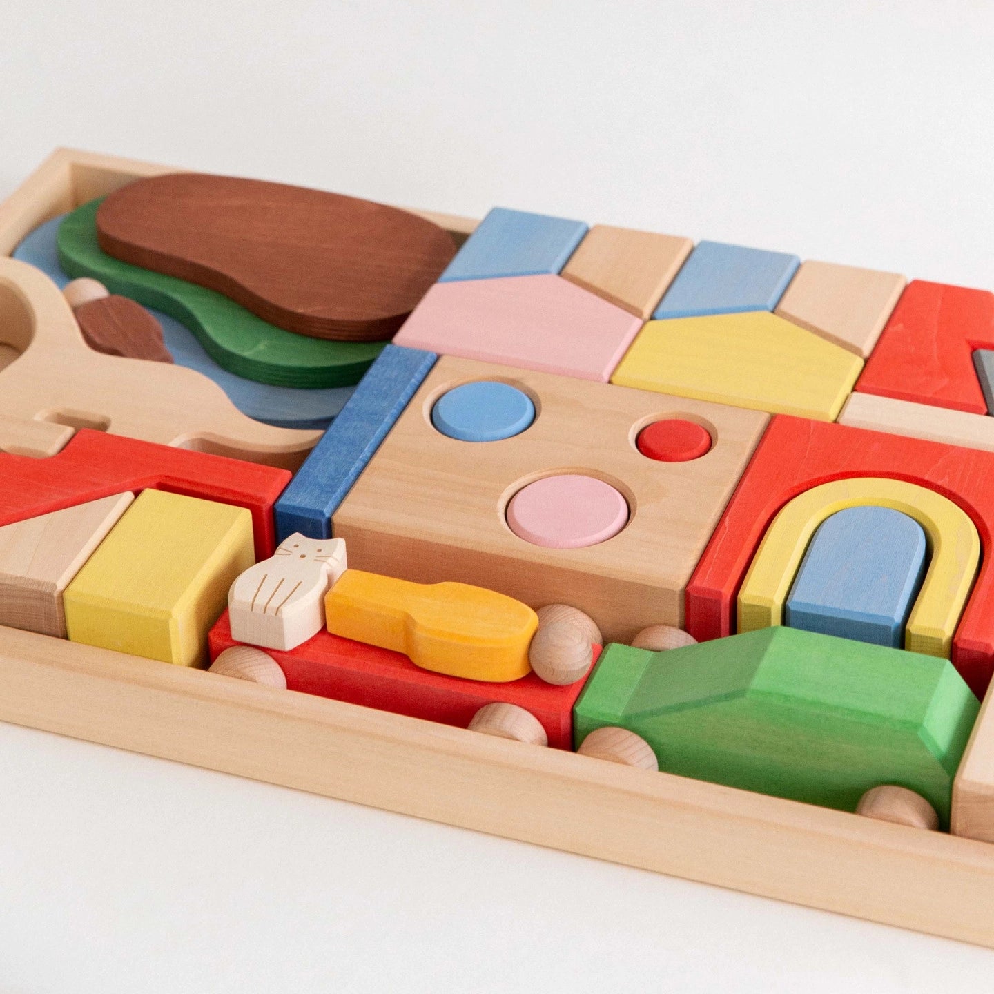 Close-up angled view of colorful geometric blocks neatly arranged inside a shallow wooden storage tray