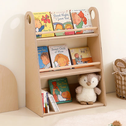 Angled view of a marine-grade plywood face-out toddler bookshelf holding colorful children's books and a plush penguin