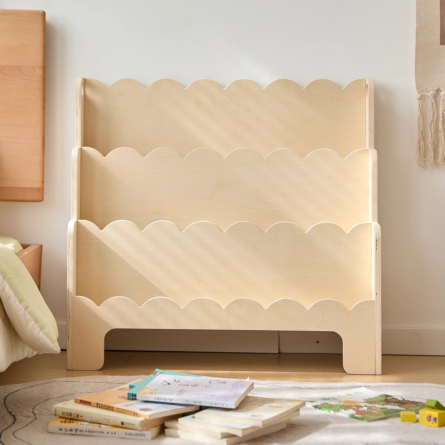 Front view of an empty plywood Montessori toddler bookshelf showing the natural wood finish and wavy shelves