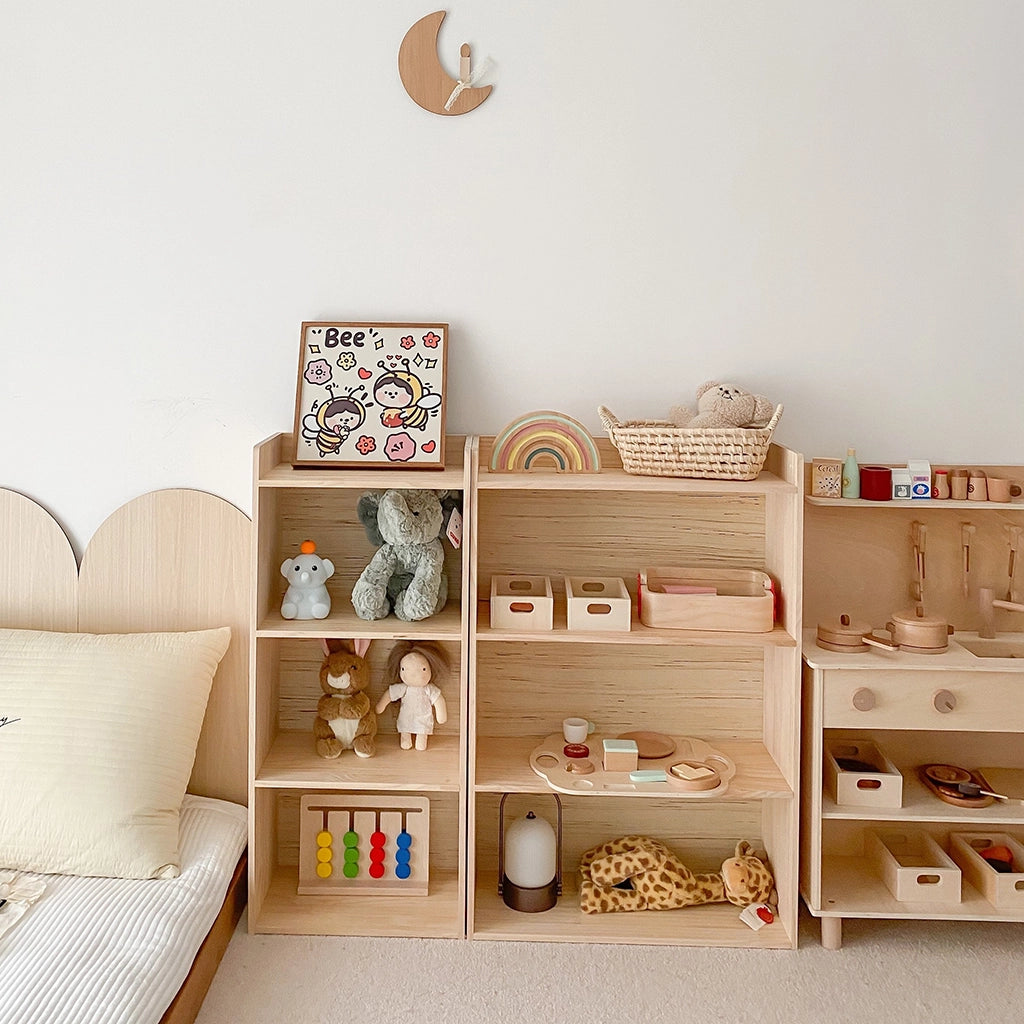 Montessori toddler storage shelf holding plush toys next to a wooden toy kitchen set