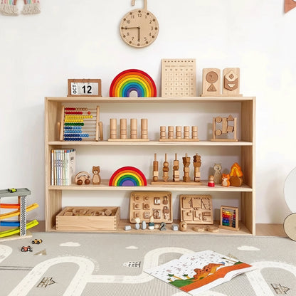 Front view of a three-tier solid pine Montessori toddler toy shelf with toys arranged under a wooden wall clock
