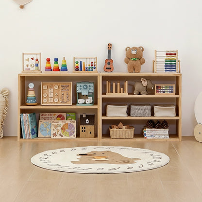 Front view of two different sized Montessori toddler toy shelves side by side with a round bear rug on the floor