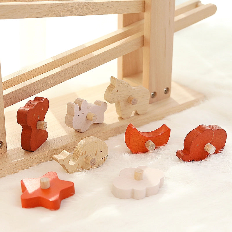 Close-up of various colorful wooden animal blocks scattered on a soft white surface beneath the ramp toy