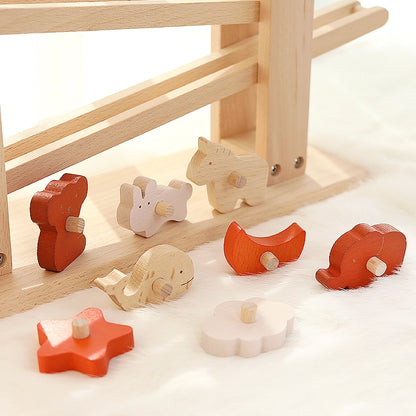 Close-up of various colorful wooden animal blocks scattered on a soft white surface beneath the ramp toy