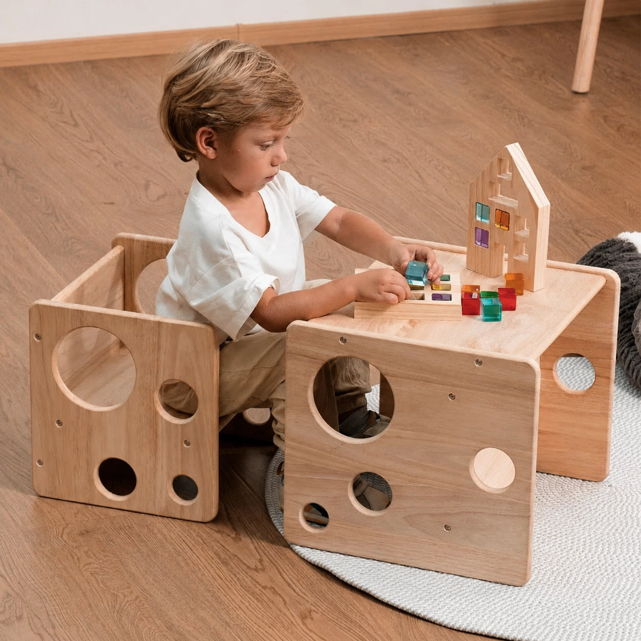 A young boy sitting at a solid rubber wood Montessori cube desk playing with colorful acrylic blocks