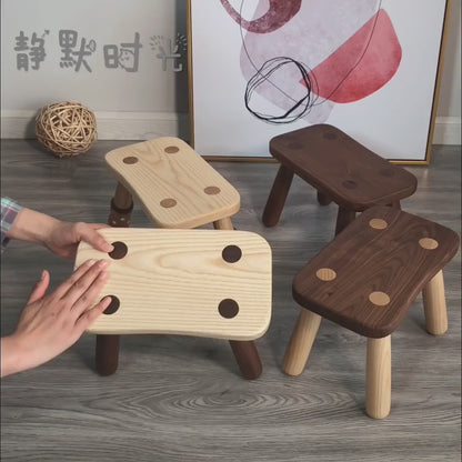 Minimalist solid wood kids low stool with rounded edges, natural wood grain, and sturdy legs, displayed to highlight its craftsmanship and everyday functionality.