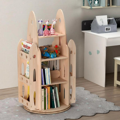 Side-angled view of a rocket rotating bookshelf with toys on a grey scalloped rug next to a white desk
